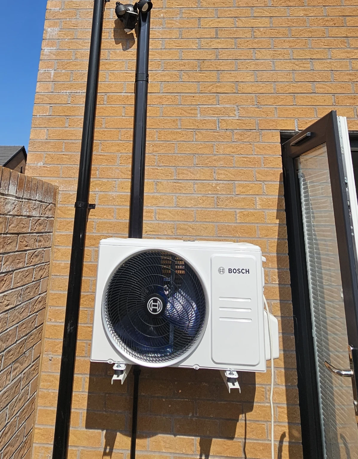 Bosch outdoor unit wall-mounted on a sunny new-build